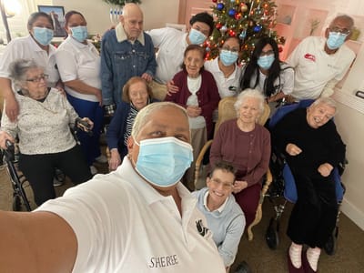 Staff and residents posing together by a decorated Christmas tree