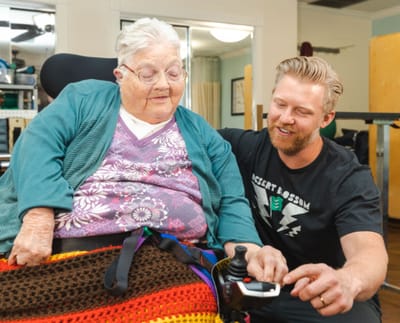 Staff assisting a resident with a device