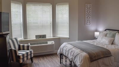 Brightly decorated private resident room with a bed and chair
