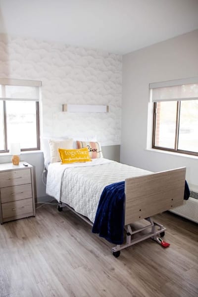 A well-furnished resident room with a bed and windows