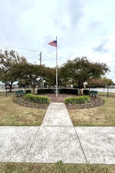 Flagpole surrounded by landscaped area with benches