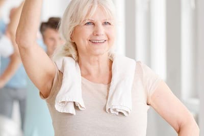 Senior woman exercising with a towel around her neck