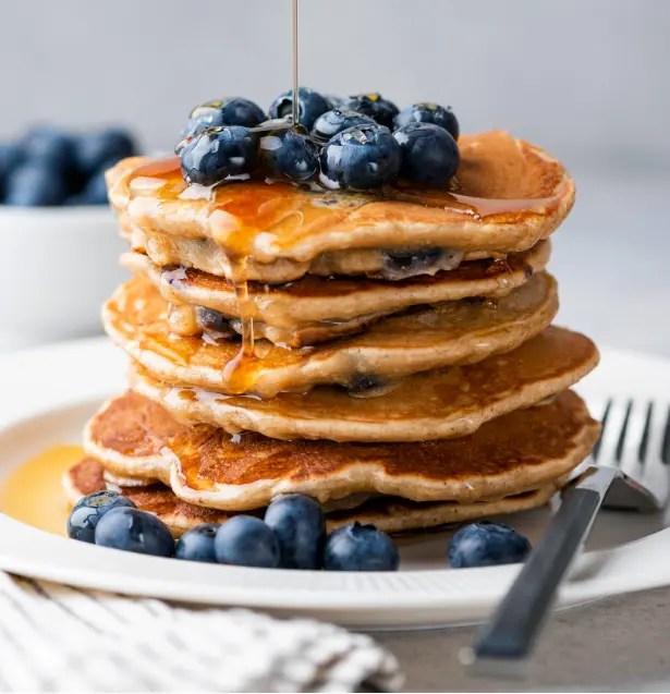 Stack of pancakes topped with blueberries and syrup