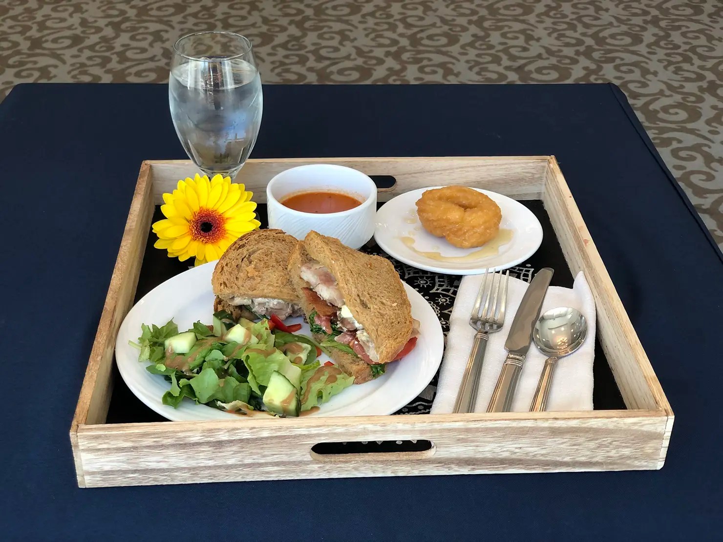 A meal tray with salad, sandwich, and dessert on a table
