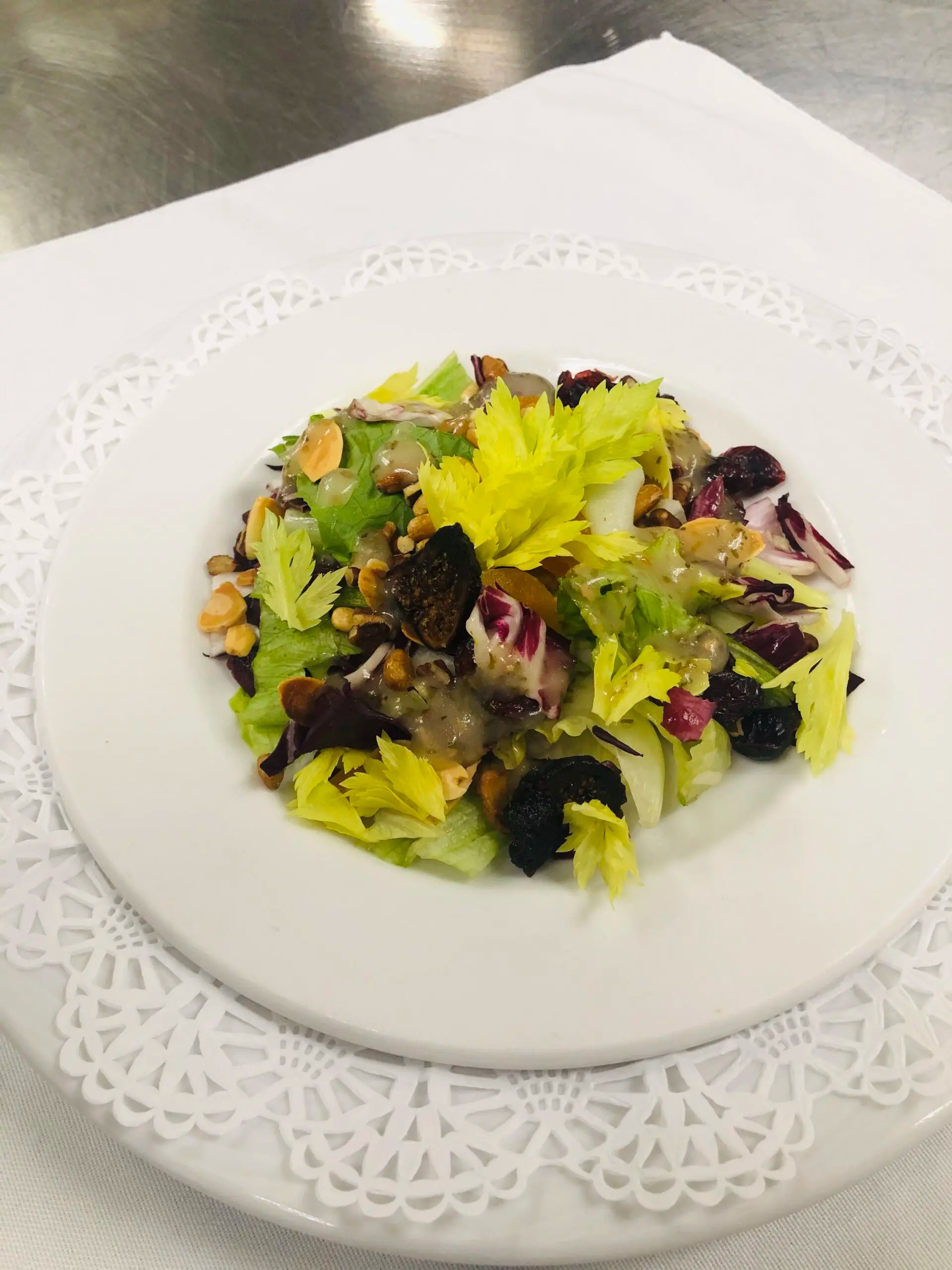 A fresh salad with greens and nuts on a white plate