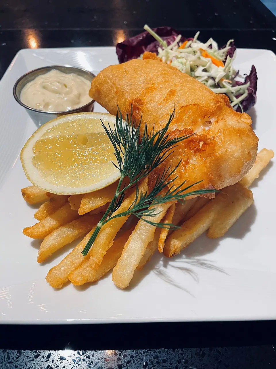 Plate of fish and chips with coleslaw and sauce