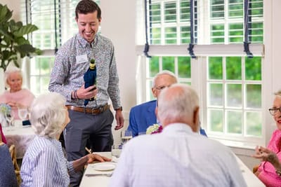 Residents enjoy a meal with staff at the dining table