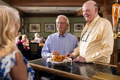 Residents enjoying food and conversation in a dining area