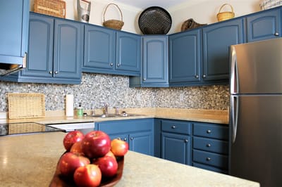 Bright kitchen with blue cabinets and fresh apples on the counter