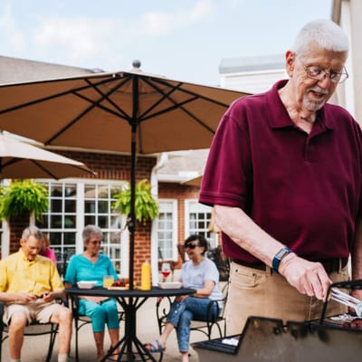 A resident grilling while others enjoy an outdoor gathering