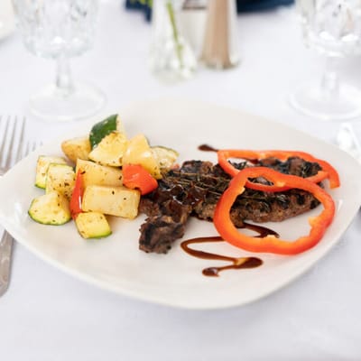 Plate of grilled steak with vegetables and garnish