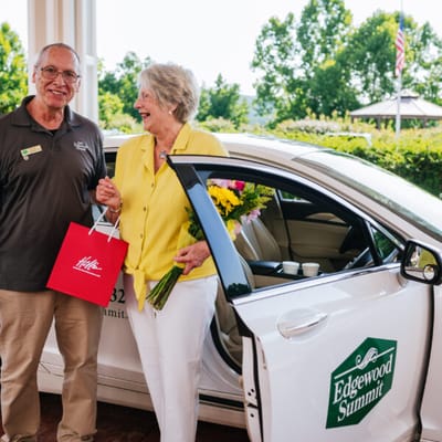 Staff member greeting a resident by a facility vehicle