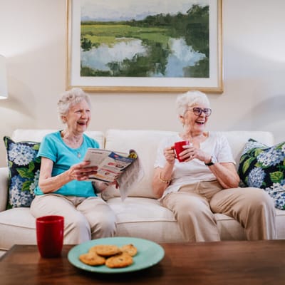 Two residents enjoying snacks and conversation in a cozy living room