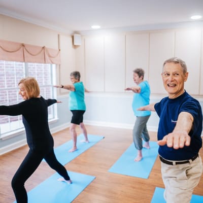 Residents participating in a yoga class in a bright activity room