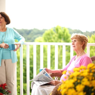 Two residents enjoying a sunny outdoor space with drinks