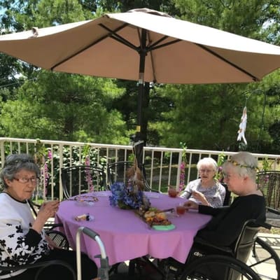 Residents enjoying drinks at an outdoor table under an umbrella