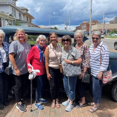 Residents and staff posing by a vintage car
