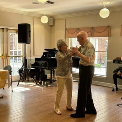 Two residents dancing in a bright activity room
