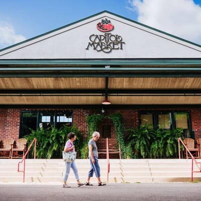 Two women walking near a market building.