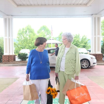 Two residents carrying bags outside the facility