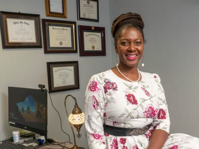 Staff member in an office setting with diplomas on the wall