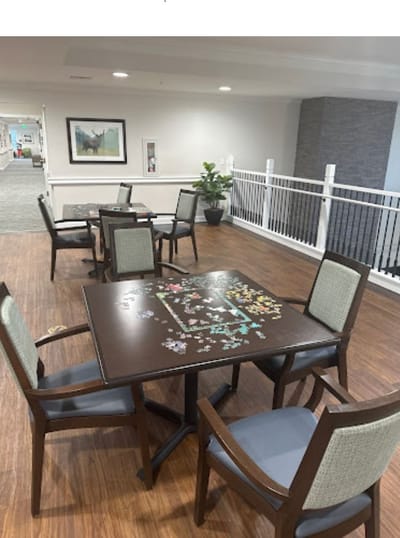 Chairs and tables in a common area with a puzzle on a table.