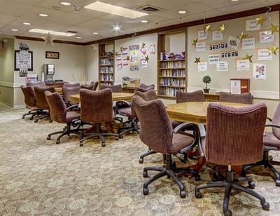 A well-furnished activity room with tables and chairs