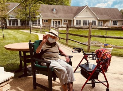 An elderly woman sitting in a garden area of the facility