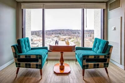 Two teal chairs facing a scenic view from a large window