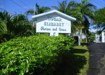 Signage for Hogar Elisabet surrounded by lush greenery