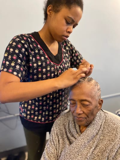 A caregiver styling the hair of a senior resident