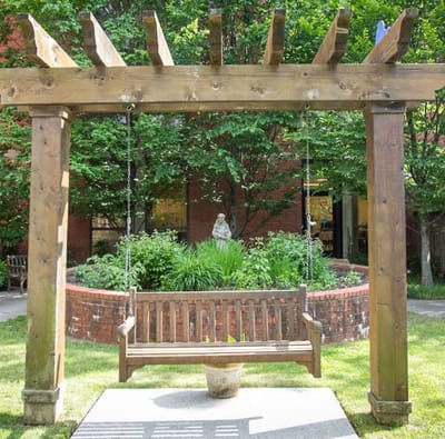 Outdoor swing bench under a wooden pergola