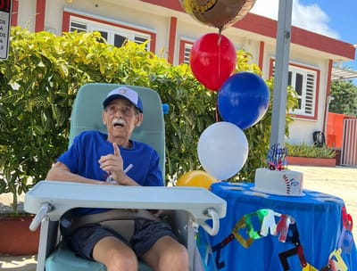 Resident celebrating with balloons and cake at outdoor party
