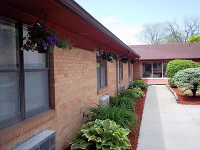 Pathway outside a senior living facility with flowers and greenery