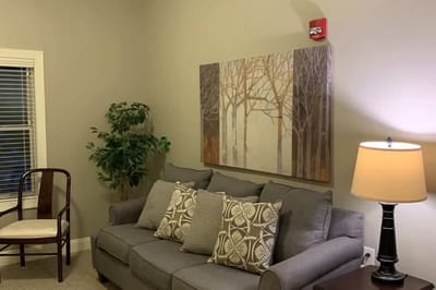Cozy living room with couch, artwork, and lamp