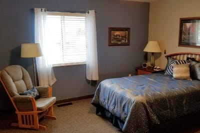 A cozy private resident room with a bed and chair