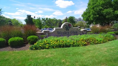 Sign for Wesley Glen surrounded by flowers and greenery
