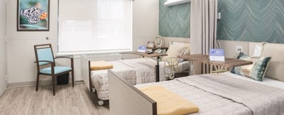Bright shared room with two beds and a chair
