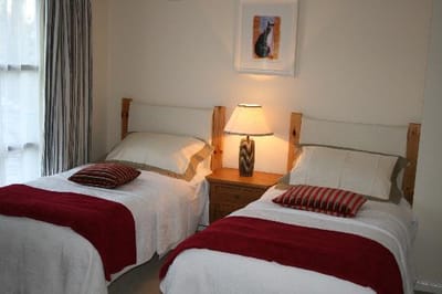 A bright shared room with two beds and a lamp