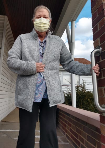 Woman in a mask standing outside a facility