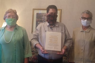 Three individuals holding a certificate indoors.