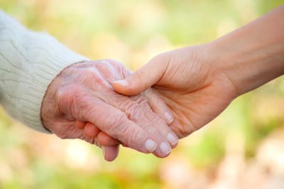 Two hands clasped together in a supportive gesture.