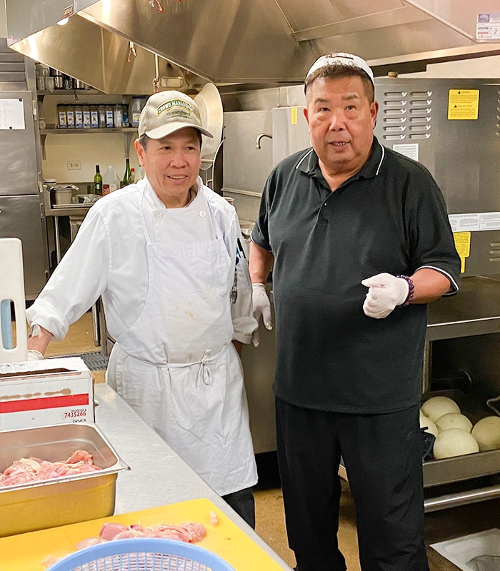 Two kitchen staff preparing food in the kitchen