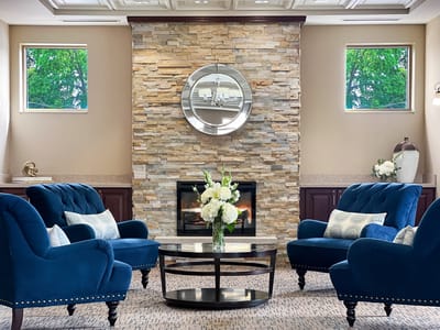 Cozy common area with blue chairs and a stone fireplace