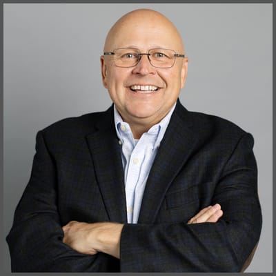 Man smiling in a blazer, posing for a professional photo