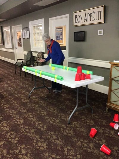 Resident participating in an activity with cups and foam rolls