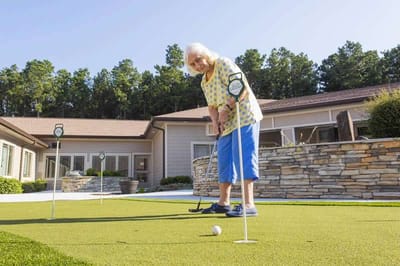 A resident playing mini-golf outdoors on a sunny day