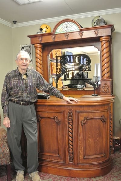 An elderly man standing next to a vintage bar setup