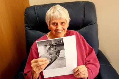 Senior resident holding a photo in a cozy chair