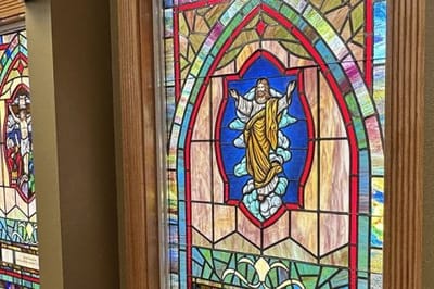 Stained glass window depicting a figure on clouds